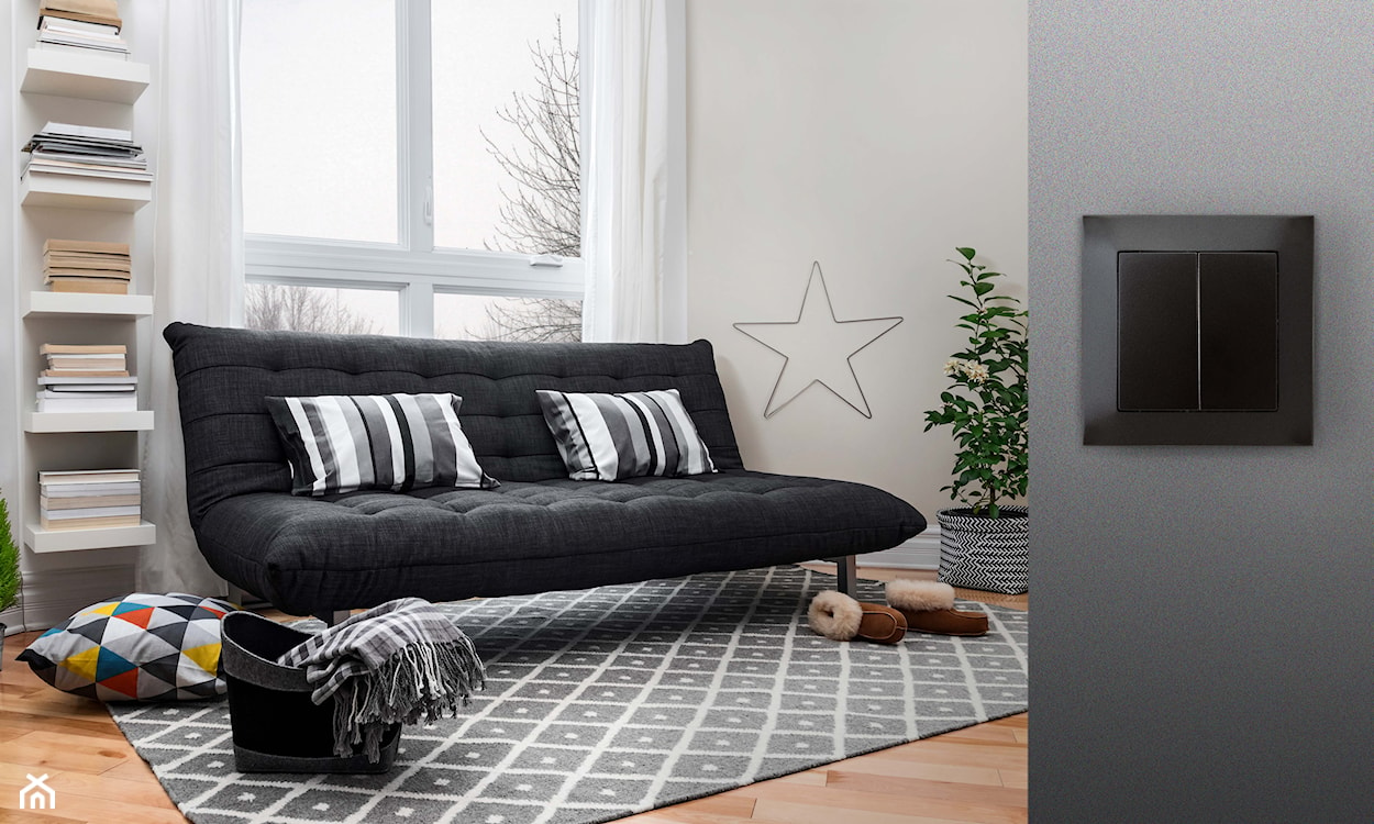 druciana gwiazda na ścianie, czarna sofa, szary dywan w białe wzory