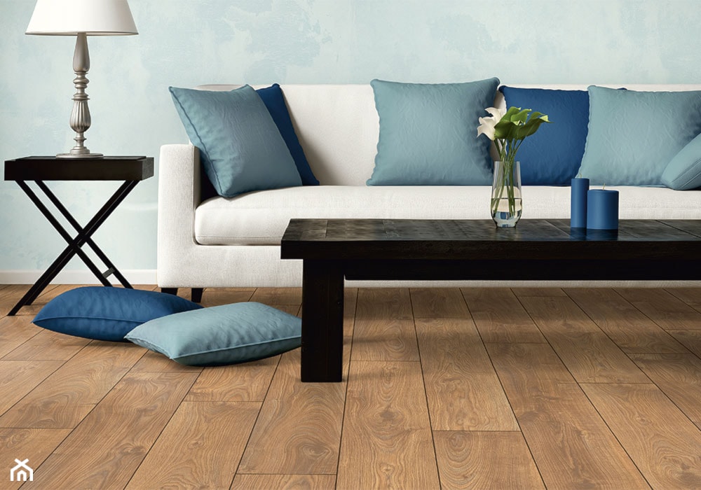 niebieskie poduszki, płytki imitujące drewno, biała sofa