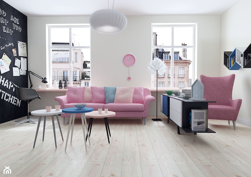 drewniana podłoga, okrągły niebieski stolik, różowa sofa, różowy fotel, farba tablicowa na ścianie