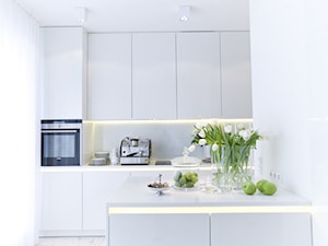 Apartament Biały - Mała otwarta biała z zabudowaną lodówką kuchnia jednorzędowa z wyspą lub półwyspem, styl minimalistyczny - zdjęcie od Chałupko Design