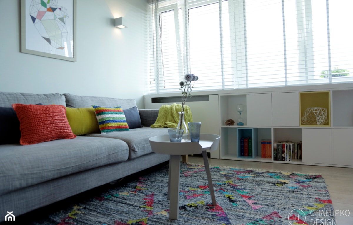 szara sofa z kolorowymi poduszkami i białe meble w salonie