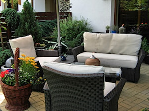 Strefa wypoczynku - Średni z podłoga z płyt betonowych z meblami ogrodowymi z donicami na kwiaty taras z tyłu domu - zdjęcie od metez