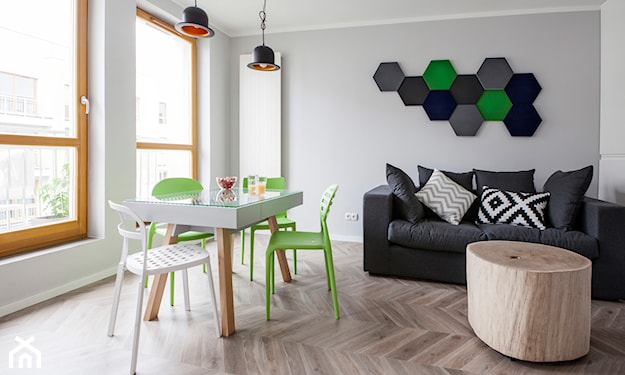 podłoga z jasnego drewna, zielone krzesło z tworzywa, ozdoba ścienna z betonowych heksagonów