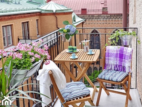 przytulny balkon z roślinami i drewnianymi meblami 