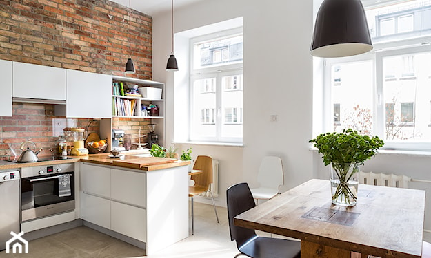 drewniany stół, ceglana ściana, biała kuchnia
