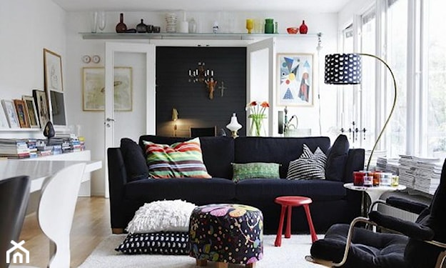 metalowa lampa podłogowa, czerwony stolik, kremowy dywan, czarna sofa, zielona poduszka
