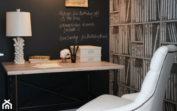 czarna ściana, tapeta z książkami, fotel z białym obiciem, drewniane biurko