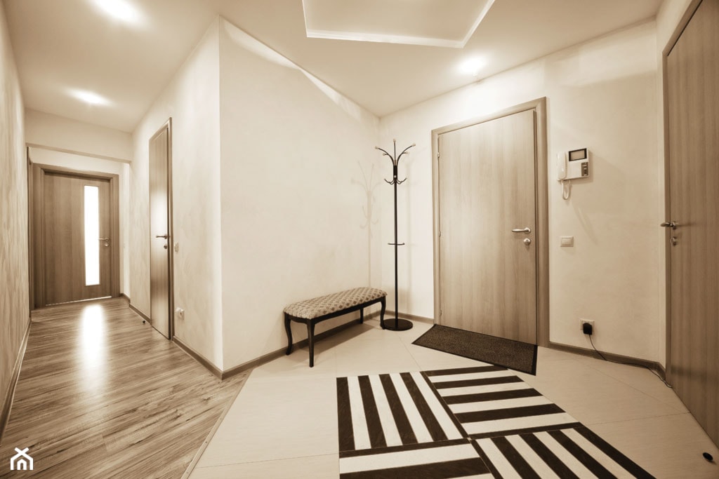 drewniana podłoga, dywanik w biało-czarne paski, beżowe płytki w korytarzu