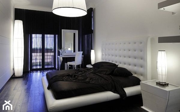 podłoga z ciemnego drewna, białe łóżko z pikowanym zagłówkiem, lampa wisząca z białym abażurem