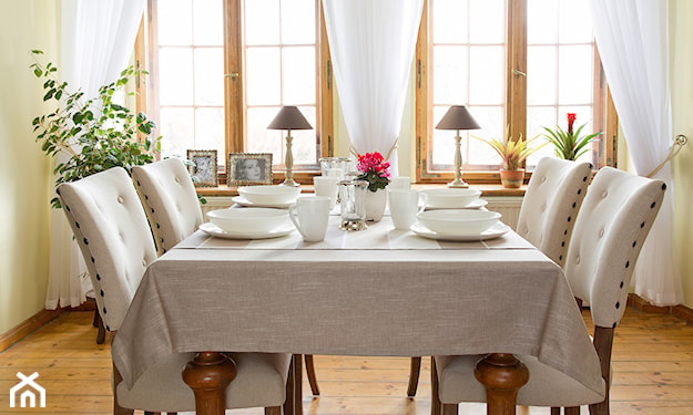stół na drewnianych nogach, biała zastawa stołowa, kremowe pikowane krzesła, białe zasłony