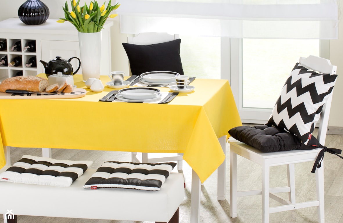 żółty obrus, białe krzesła, biało-czarne poduszki, drewniana deska do krojenia