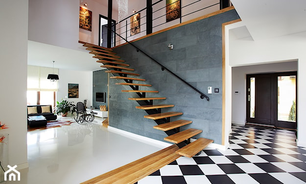 drewniane schody bez balustrady, betonowe płytki na ścianie, biało-czarne płytki