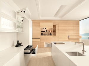 Kuchnia - wnętrza - Duża otwarta z kamiennym blatem biała z zabudowaną lodówką z podblatowym zlewozmywakiem kuchnia w kształcie litery l z wyspą lub półwyspem z oknem, styl minimalistyczny - zdjęcie od Blum