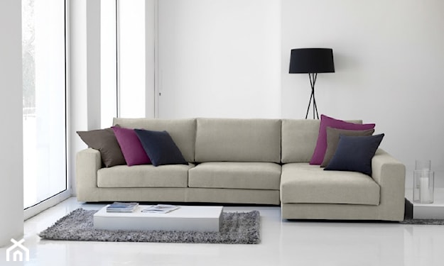 szara sofa, metalowa lampa podłogowa z czarnym abażurem, fioletowa poduszka, czarna poduszka, szary dywanik, biały stolik