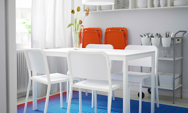 biały stół i krzesła, niebieski dywan, metalowa szafka, biała lampa wisząca z białym abażurem