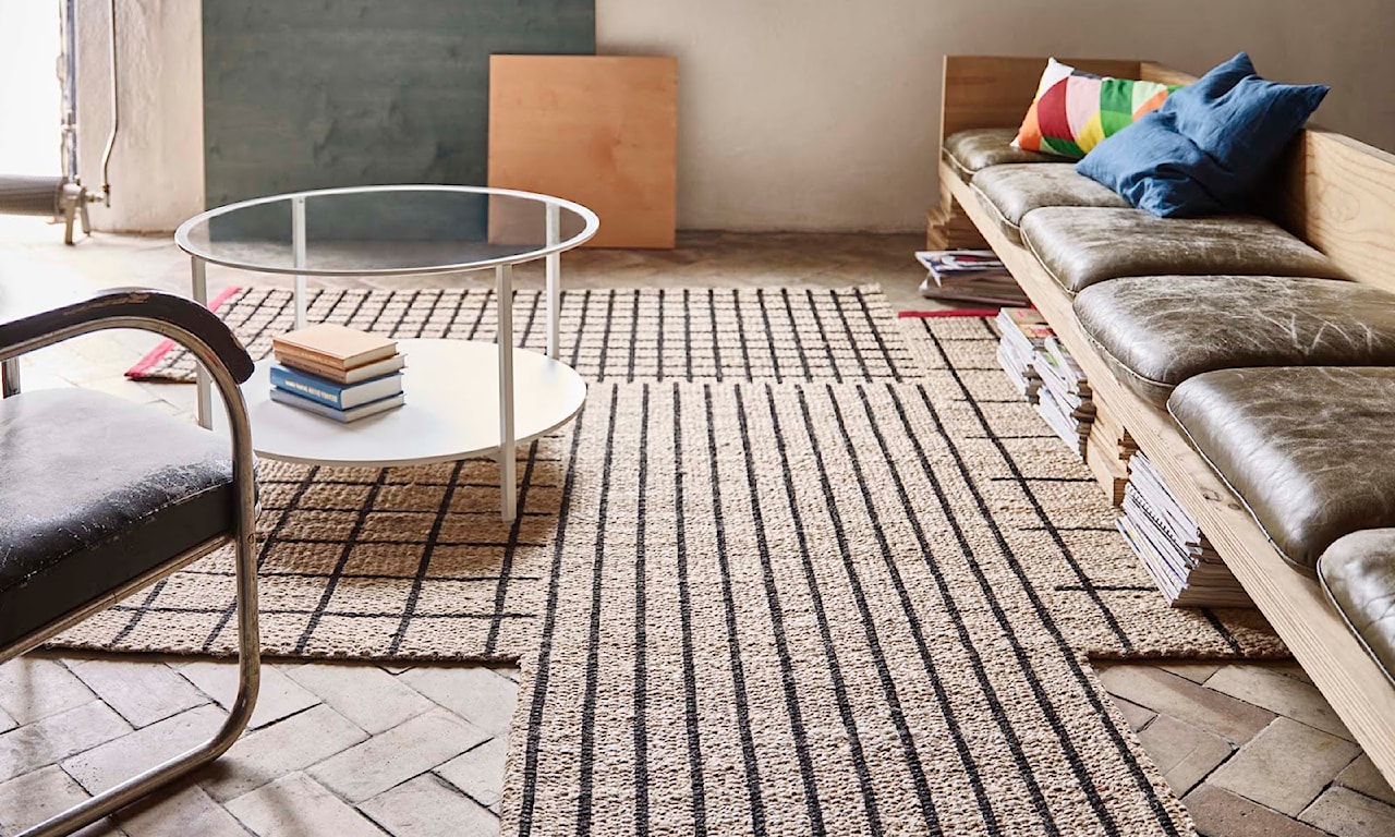 dywan z naturalnego materiału, beżowy dywan, szklany stolik, drewniana podłoga w jodełkę