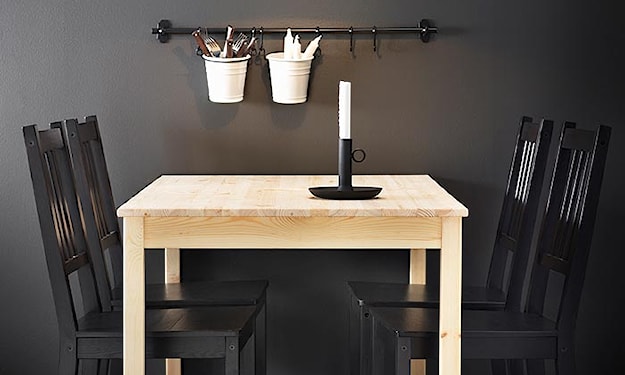 stół z jasnego drewna, czarne krzesła, białe pojemniki z metalu