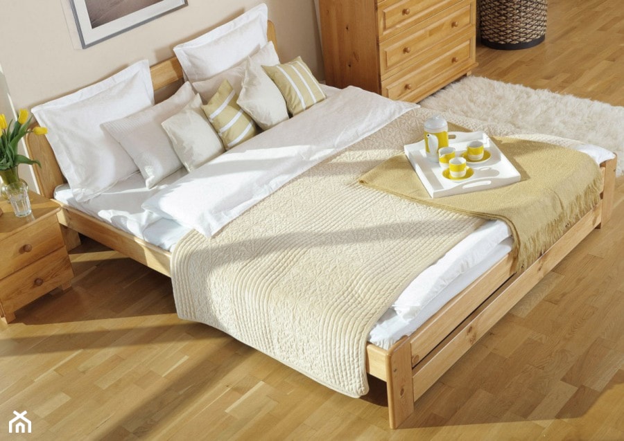 drewniana rama łóżka, drewniana podłoga, biały dywanik, beżowa narzuta