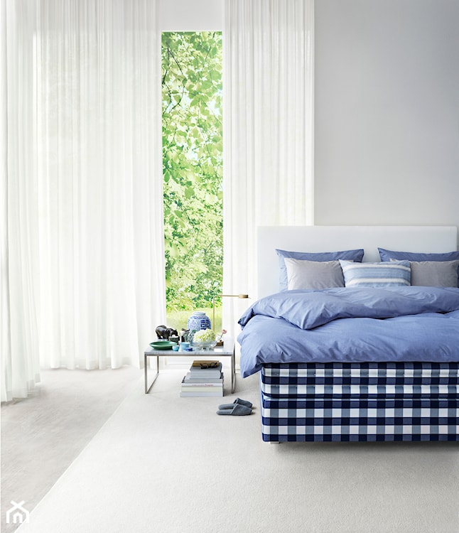 niebieska pościel, łóżko w granatową kratę Hästens, białe firany, biały dywan