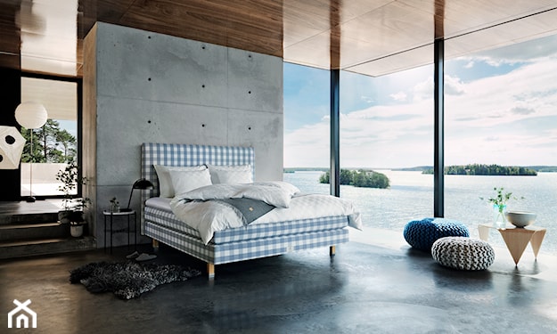 łóżko Hästens, szara pufa, płyty betonowe, biała pościel