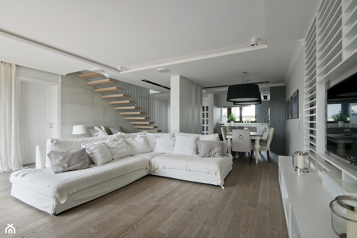 salon w stylu skandynawskim, duży biały narożnik, drewniana podłoga w chłodnym odcieniu