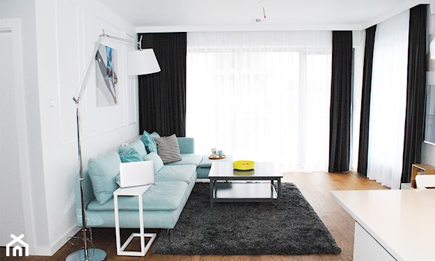 drewniana podłoga, grafitowy dywan, miętowa sofa, czarne długie zasłony, metalowa lampa podłogowa z białym abażurem