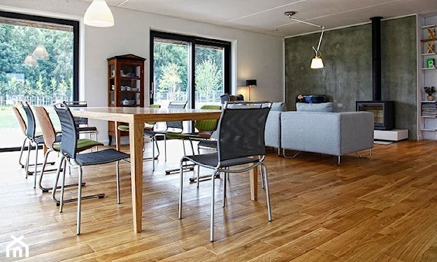 drewniana podłoga w salonie, drewniany stół, szara sofa, biała lampa wisząca