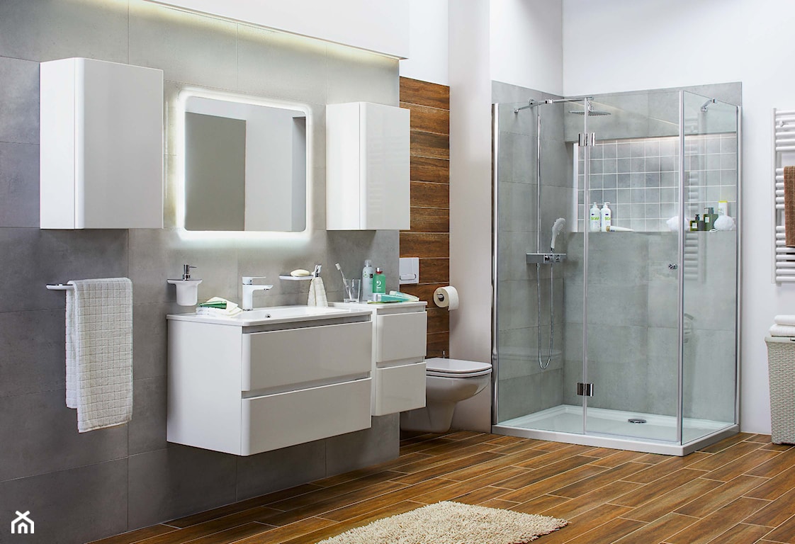 białe meble łazienkowe, lustro bez ramy z podświetleniem, płytki gresowe imitujące drewno, beżowy dywanik łazienkowy