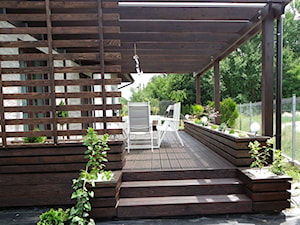 Zabudowa tarasu - Średni z podłogą z desek z meblami ogrodowymi z donicami na kwiaty taras z tyłu domu - zdjęcie od Bryniak Woodworking