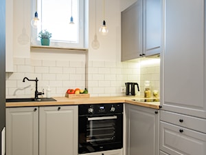 Mokotowska Kawalerka - Mała otwarta z salonem biała z zabudowaną lodówką z nablatowym zlewozmywakiem kuchnia w kształcie litery l z oknem, styl industrialny - zdjęcie od EG projekt