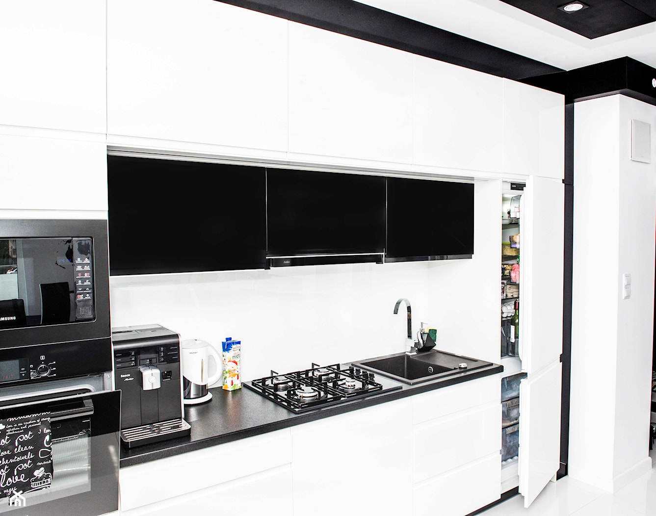Mieszkanie w Siedlcach - Białe Meble kuchenne z czarnym - Mała z salonem biała z zabudowaną lodówką z podblatowym zlewozmywakiem kuchnia jednorzędowa, styl nowoczesny - zdjęcie od Meble na wymiar Kulenty - Homebook