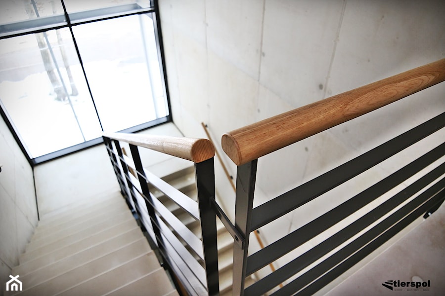 Balustrady z drewnianym pochwytem na klatce schodowej - zdjęcie od Tierspol producent schodów szklanych i całoszklanych