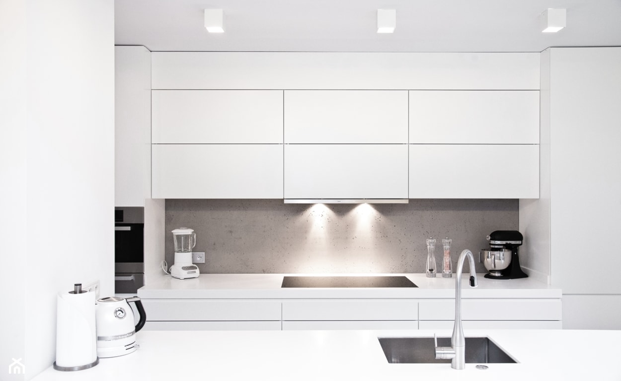 biała kuchnia minimalistyczna, biały blat, biała bateria, betonowa przestrzeń między szafkami