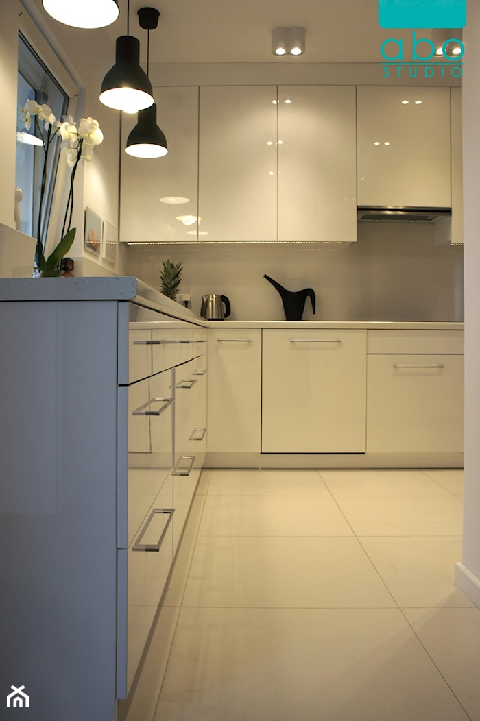 apartament Polanka- kuchnia, Poznań - Średnia z salonem biała z zabudowaną lodówką kuchnia w kształcie litery l z kompozytem na ścianie nad blatem kuchennym, styl minimalistyczny - zdjęcie od abostudio - Homebook