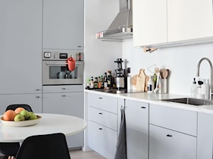 Kawalerka - Średnia zamknięta z kamiennym blatem biała z zabudowaną lodówką z nablatowym zlewozmywakiem kuchnia w kształcie litery l, styl skandynawski - zdjęcie od doxium
