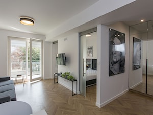 Biały, nowoczesny salon z drewnianym parkietem - zdjęcie od OHHOME - projekty, remonty, meble
