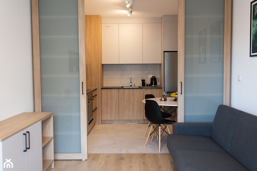 Salon z kuchnią oddzieloną przesuwnymi drzwiami - zdjęcie od OHHOME - projekty, remonty, meble