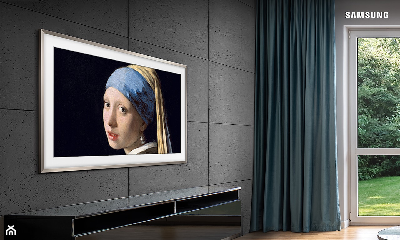 Widok na telewizor Samsung The Frame LS03BG powieszony na ścianie w salonie, tworzący ścianę telewizyjną