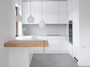 wnętrze apartamentu - Mała otwarta z salonem biała z zabudowaną lodówką z nablatowym zlewozmywakiem kuchnia w kształcie litery g, styl minimalistyczny - zdjęcie od MΛKΛ Studio