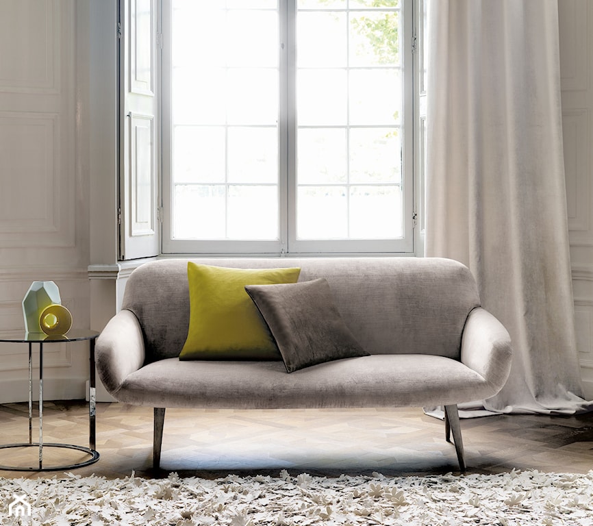 szara nowoczesna sofa z cienkimi nóżkami, seledynowa poduszka dekoracyjna