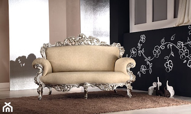 kremowa sofa na nóżkach z bogatym zdobieniem w srebrny kolorze, białe kwiaty na ścianie