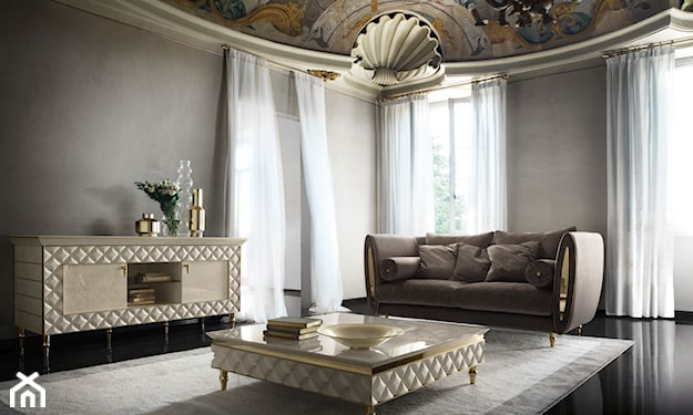 stolik ze złoceniami i pikowanym elementem dekoracyjnym, brązowa sofa, czarna podłoga z kamienia