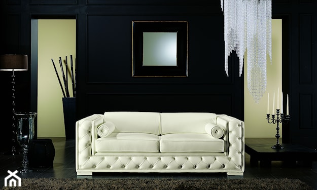 pikowana sofa w kolorze kremowym, czarny świecznik, lustro w dekoracyjnej ramie