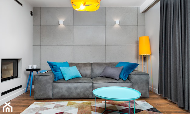 płyty betonowe, ściana betonowa, szara sofa, niebieskie poduszki