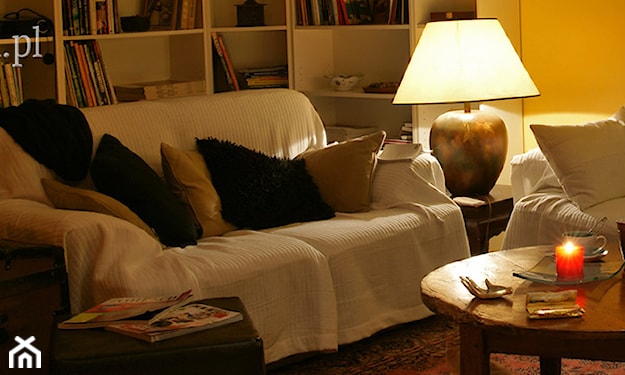 biała narzuta na sofę, drewniany stolik, złota lampa stołowa