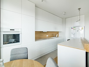 Osiedle Pod Zegarem - Duża z salonem biała z zabudowaną lodówką z podblatowym zlewozmywakiem kuchnia w kształcie litery l z wyspą lub półwyspem z oknem, styl nowoczesny - zdjęcie od Qbik Design