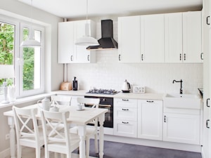 Sadyba - Średnia biała z zabudowaną lodówką z nablatowym zlewozmywakiem kuchnia w kształcie litery l, styl prowansalski - zdjęcie od Qbik Design