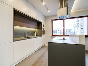 Kłobucka - Duża otwarta z salonem biała z zabudowaną lodówką z podblatowym zlewozmywakiem kuchnia dwurzędowa z wyspą lub półwyspem z kompozytem na ścianie nad blatem kuchennym, styl nowoczesny - zdjęcie od Qbik Design
