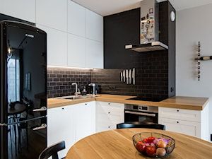 POMARAŃCZARNIA - Mała z salonem biała czarna z zabudowaną lodówką z podblatowym zlewozmywakiem kuchnia w kształcie litery l - zdjęcie od Qbik Design