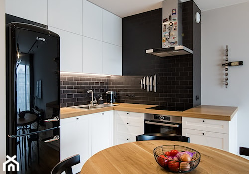 POMARAŃCZARNIA - Mała z salonem biała czarna z zabudowaną lodówką z podblatowym zlewozmywakiem kuchnia w kształcie litery l - zdjęcie od Qbik Design